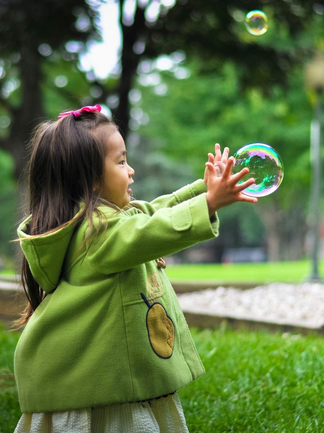 Young girl in a green coat playing with bubbles on a Calgary playground