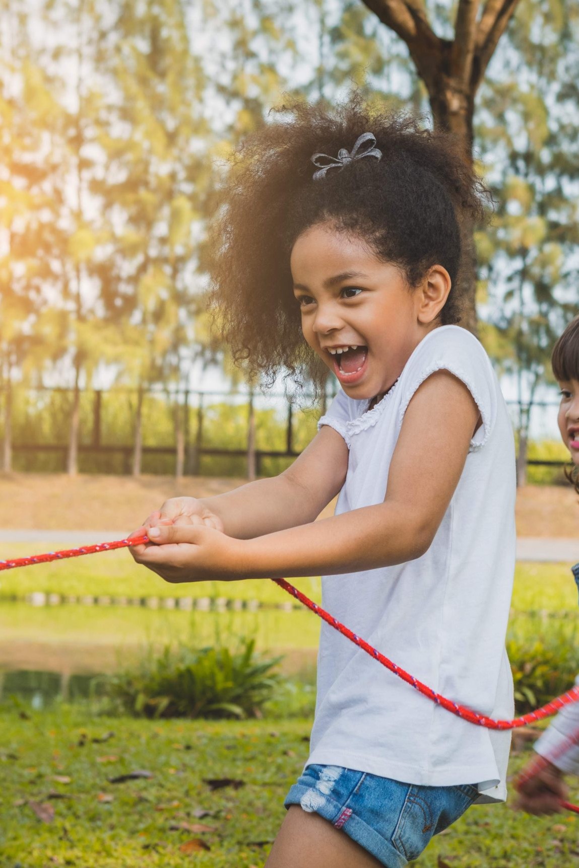 Two girls playing tug of war at Calgary daycare in outdoor field