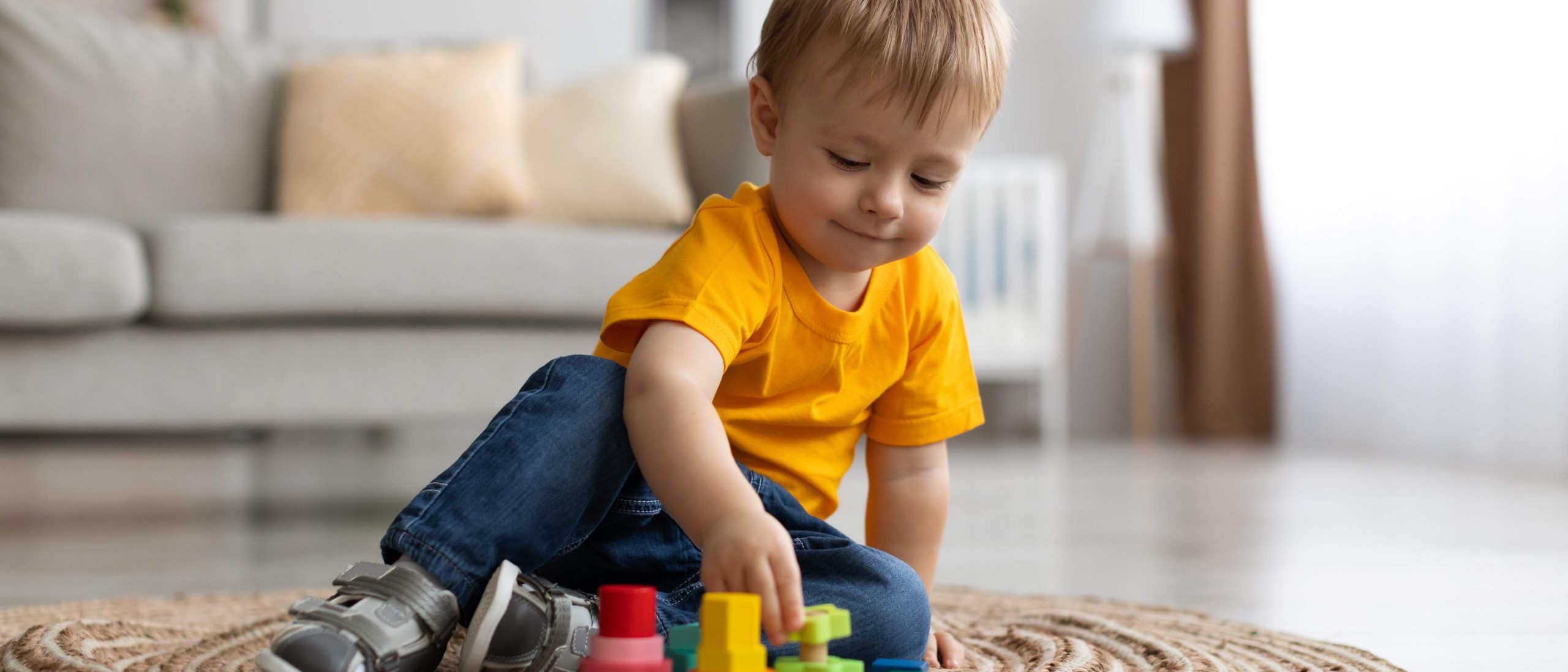Boy sitting on the floor stacking colorful blocks at a Calgary childcare centre